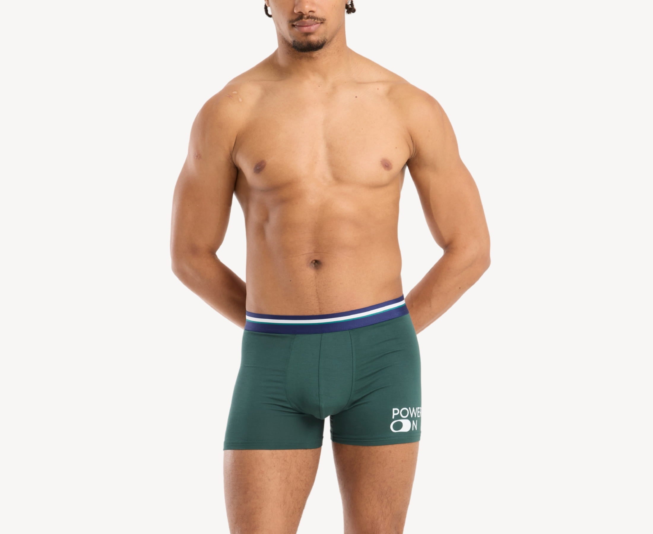 Front view of model wearing men’s 95% micromodal boxer brief in emerald green with power-on print and striped navy waistband, soft stretch and smooth finish