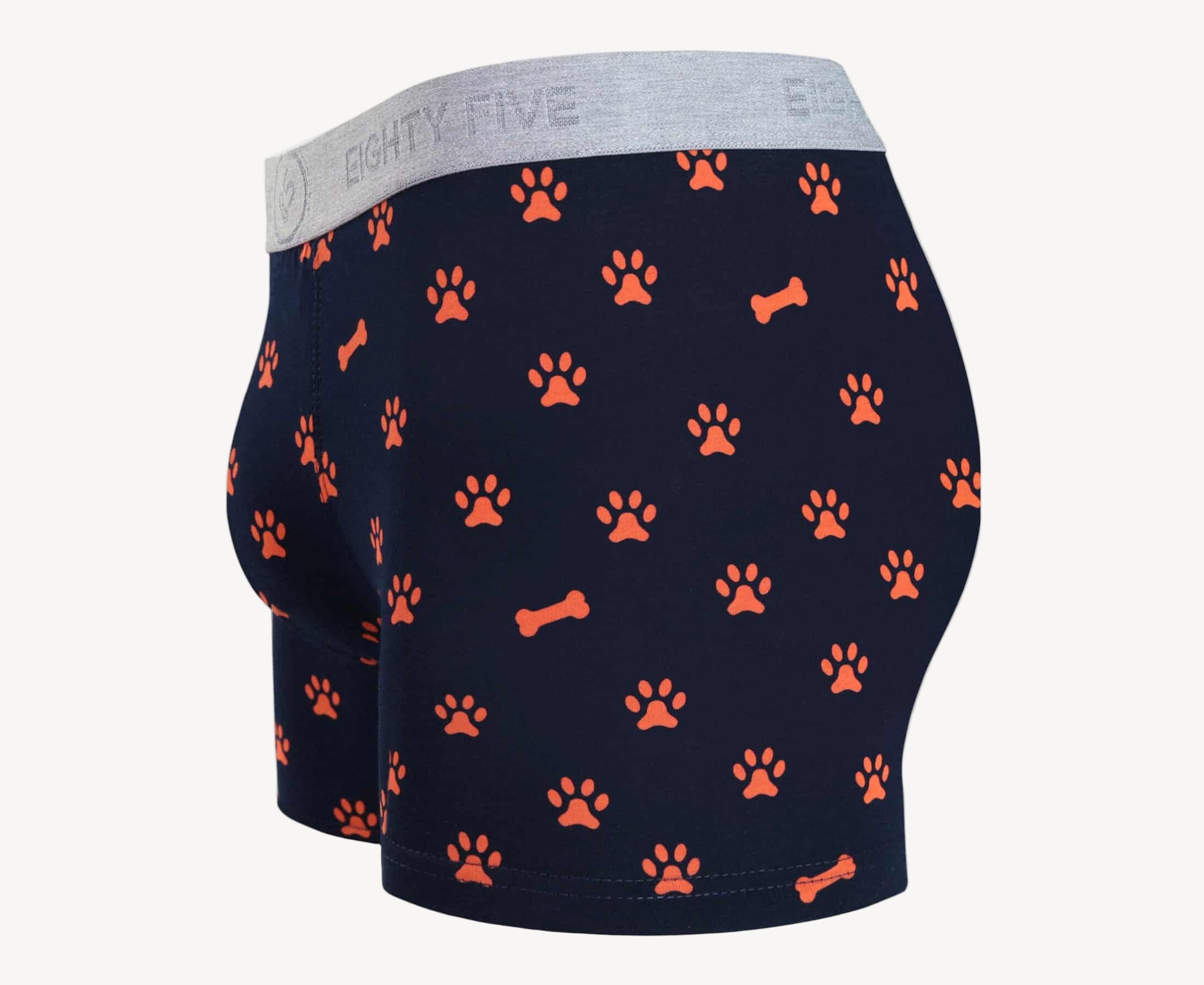 Side view of men’s 95% cotton boxer brief in navy with orange paws and bones print, contoured pouch, and tailored leg cut