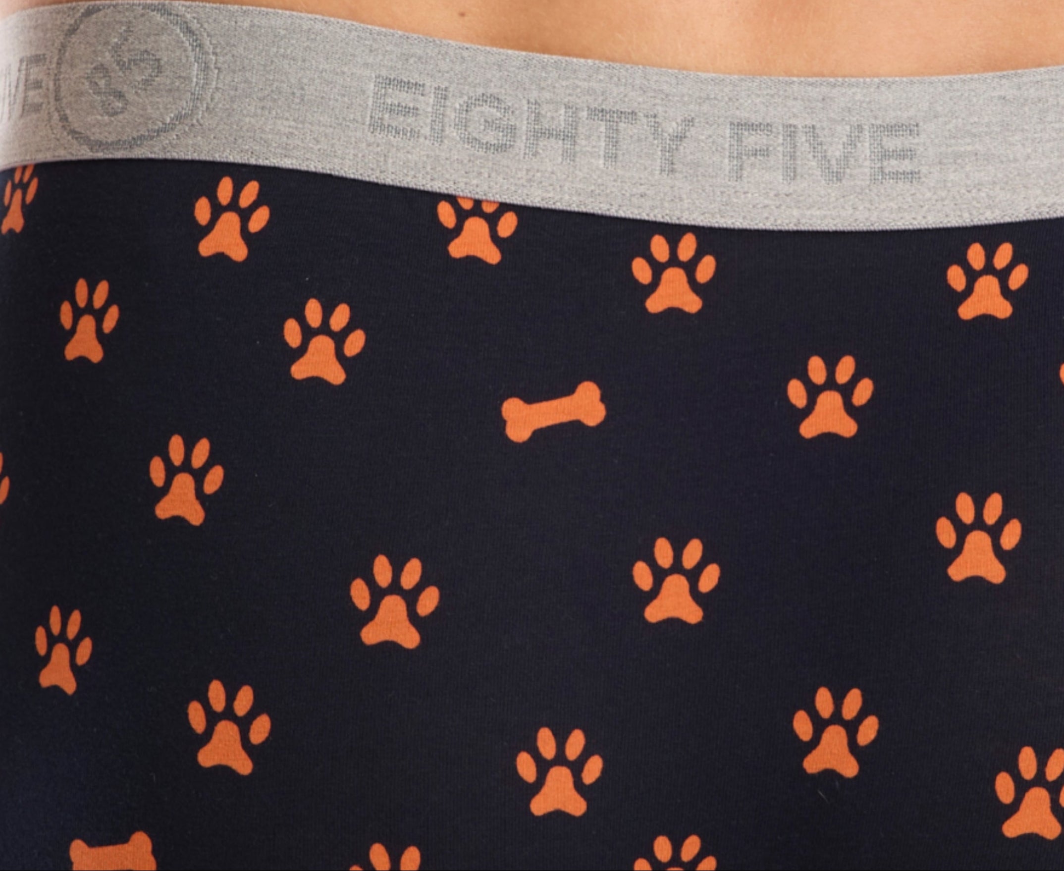 Navy fabric with orange paws and bones pattern and 'EIGHTY FIVE' branding on the gray waistband