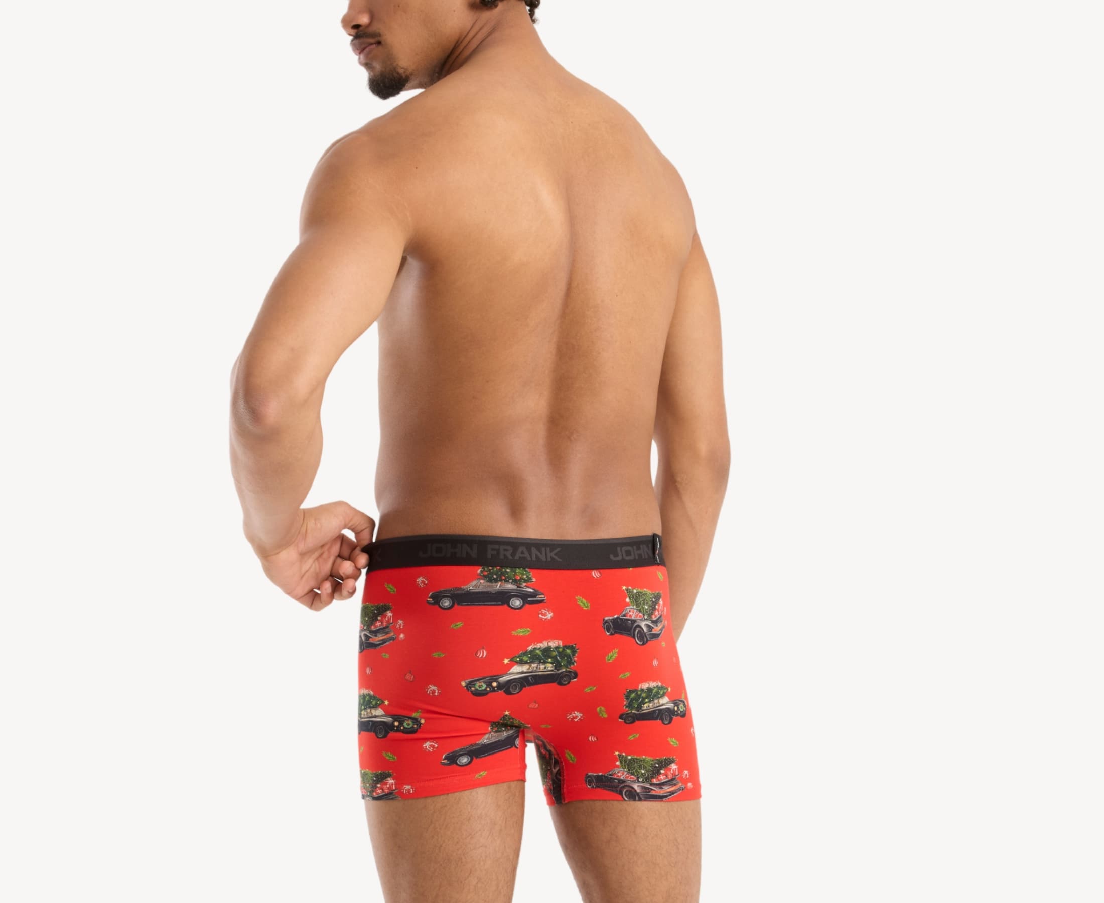 Back view of male model wearing men’s 95% cotton boxer brief in red with Christmas tree shopping print, showing waistband detail