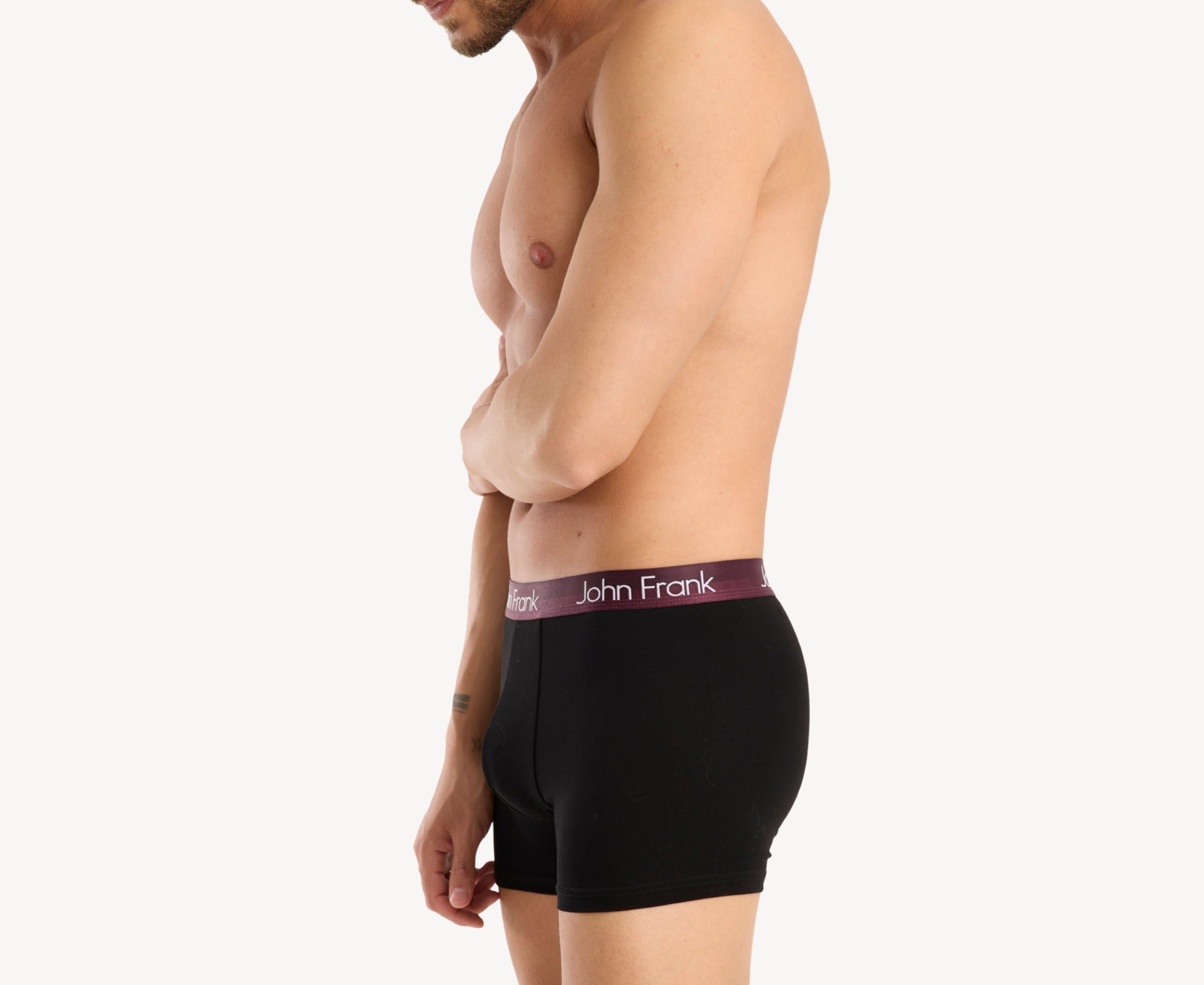 Side view of model wearing men’s 95% cotton boxer brief in black with burgundy shiny waistband, contoured pouch, and tailored leg cut