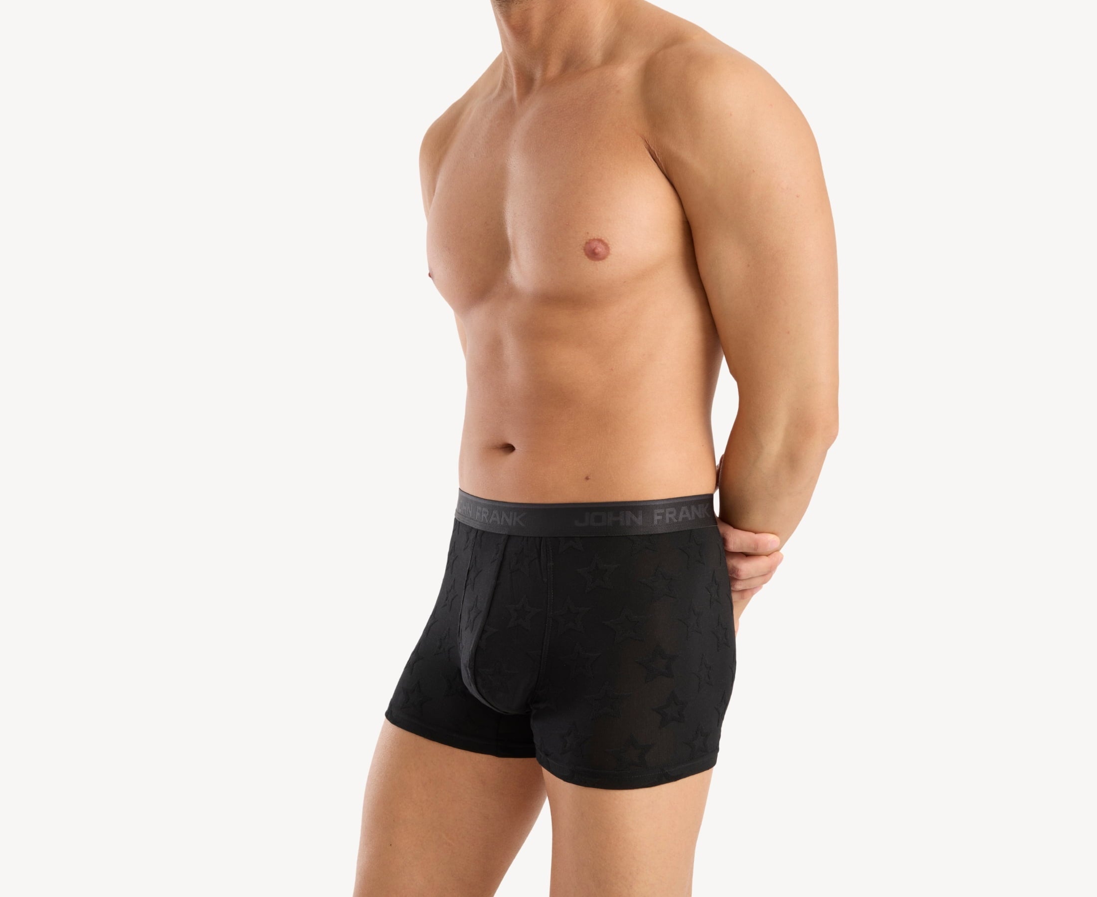 Side view of model wearing men’s 95% micromodal boxer brief in black with jacquard stars pattern, showcasing contoured pouch, and tailored leg cut