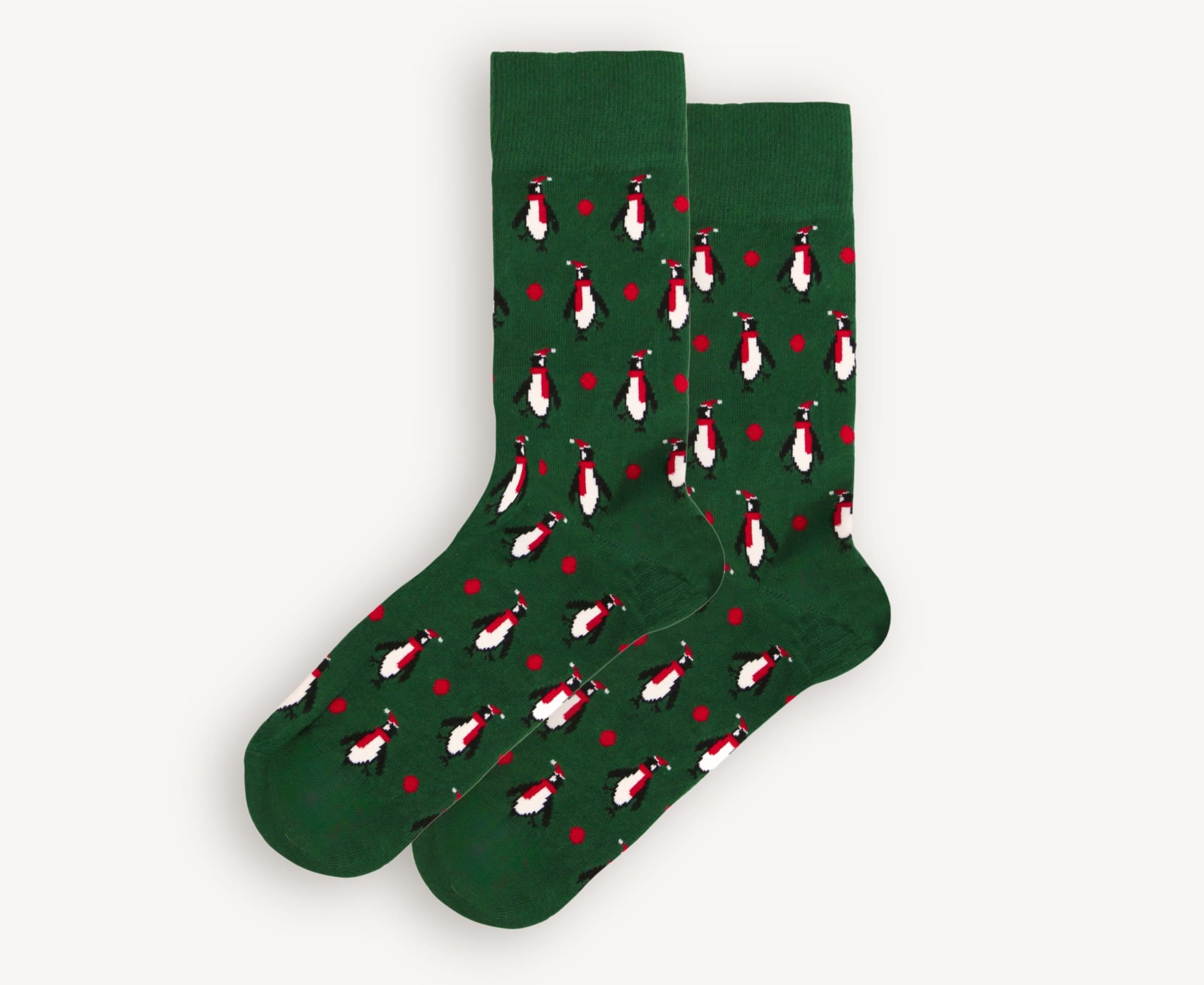 Flat lay of men’s 80% cotton crew socks in deep green with winter penguin print wearing scarves and hats, soft knit fabric with hand-linked toe and festive detailing