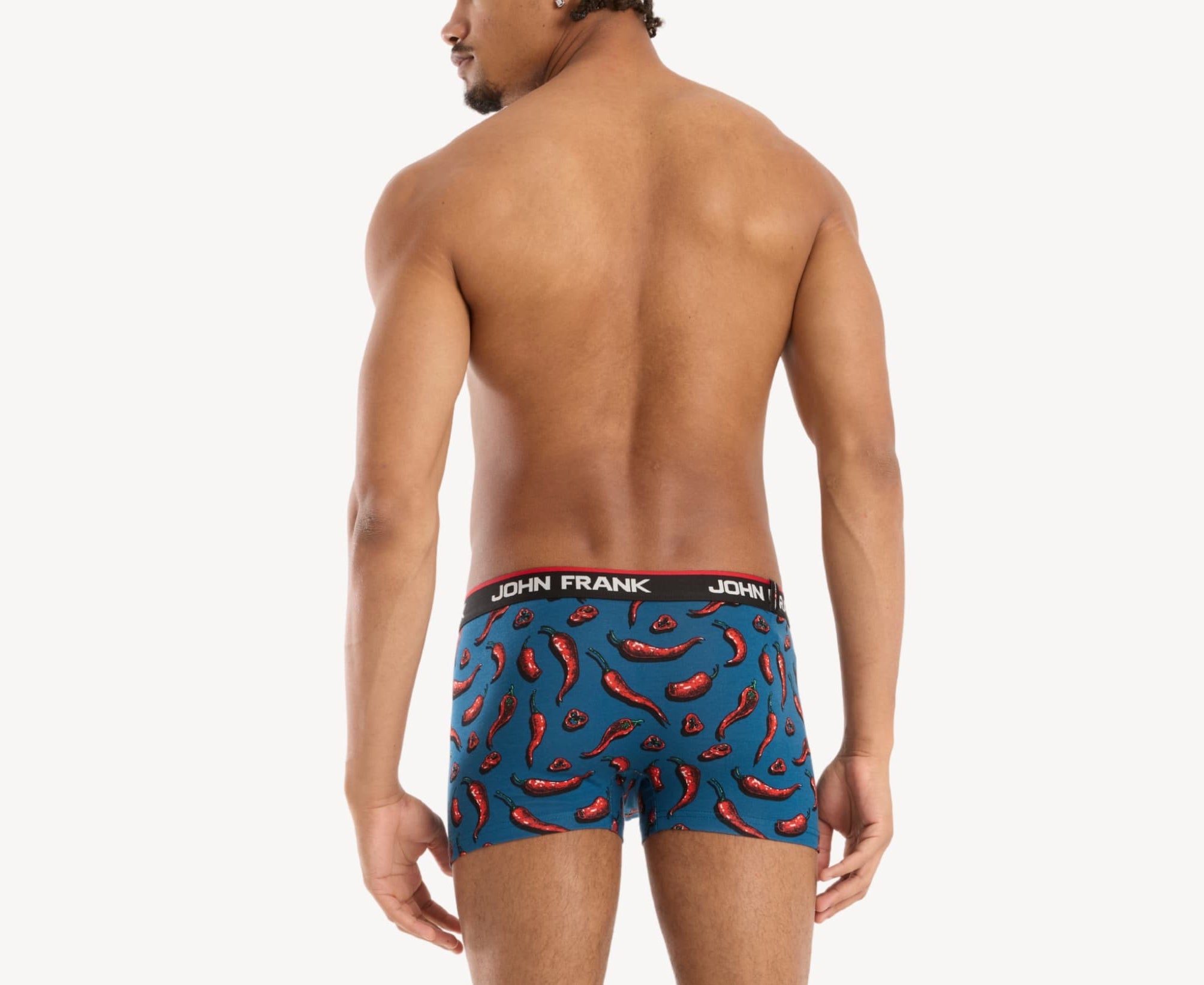 Back view of male model wearing men’s 95% cotton boxer brief in blue with red chili pepper print, showing waistband detail