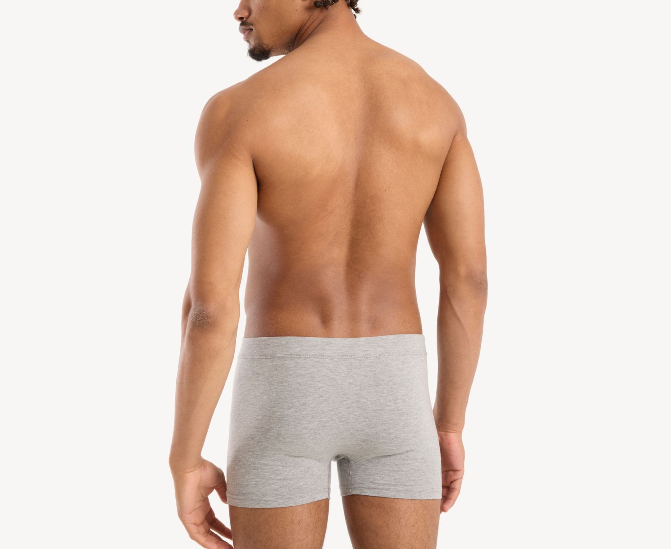 Back view of model wearing men’s 95% cotton boxer brief in stone gray with fabric-covered waistband and rear detail