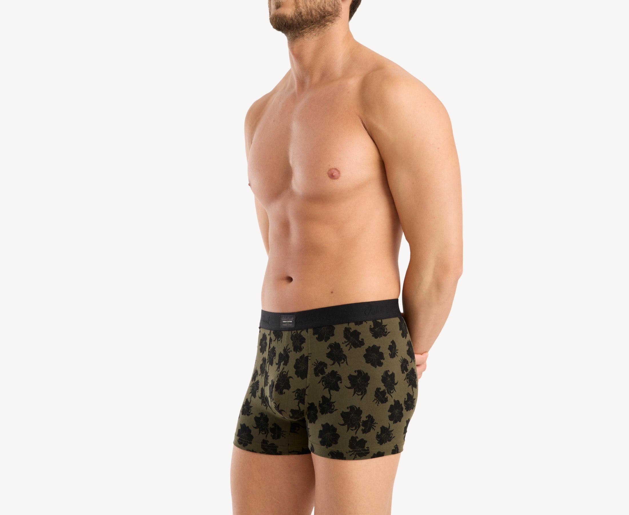 Side view of male model wearing men’s 95% cotton boxer brief in olive with black hibiscus print, contoured pouch, and tailored leg cut