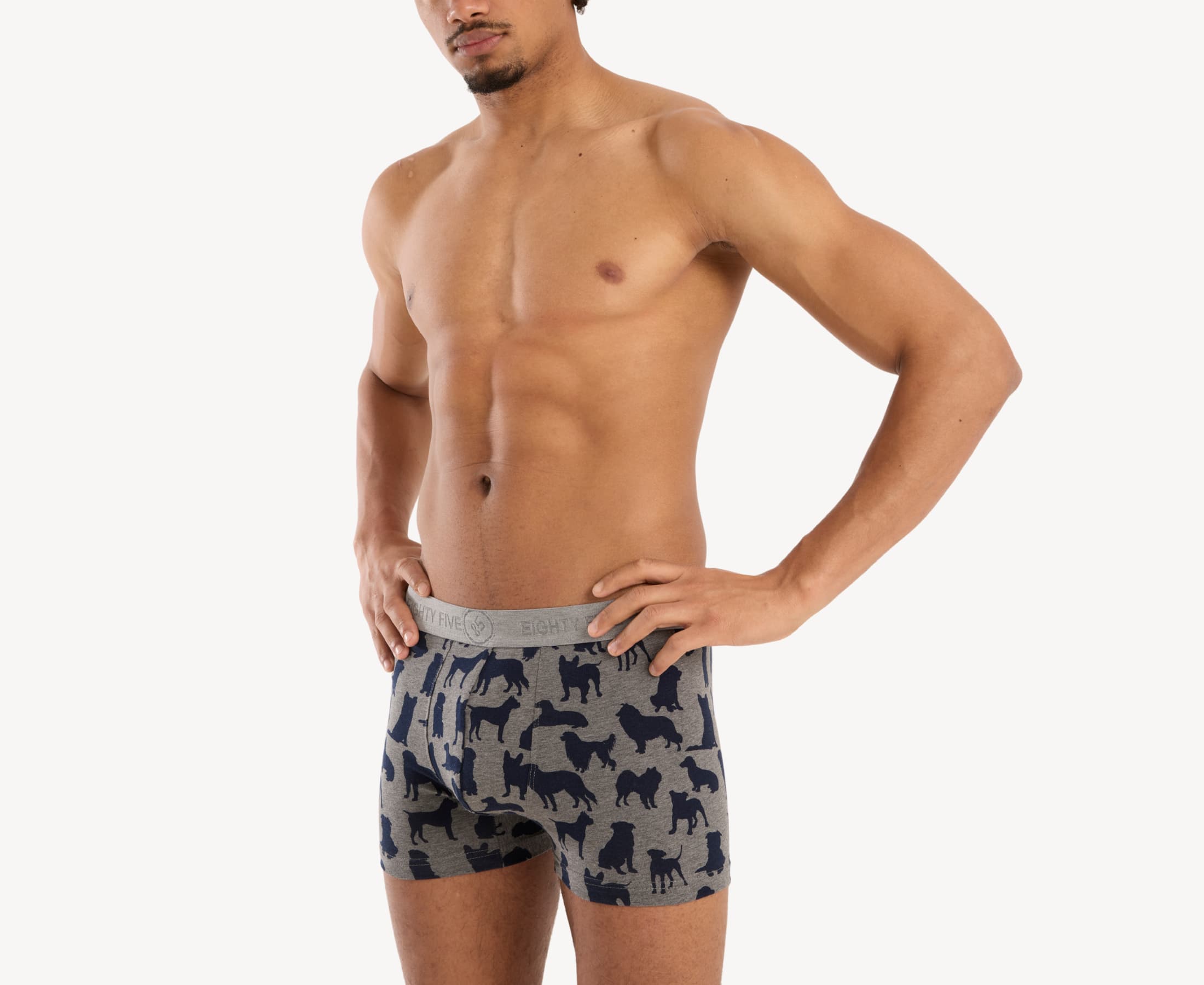 Quarter side view of male model wearing men’s 95% cotton boxer brief in heather gray with navy dog silhouette print, showing smooth waistband and natural fit through the leg