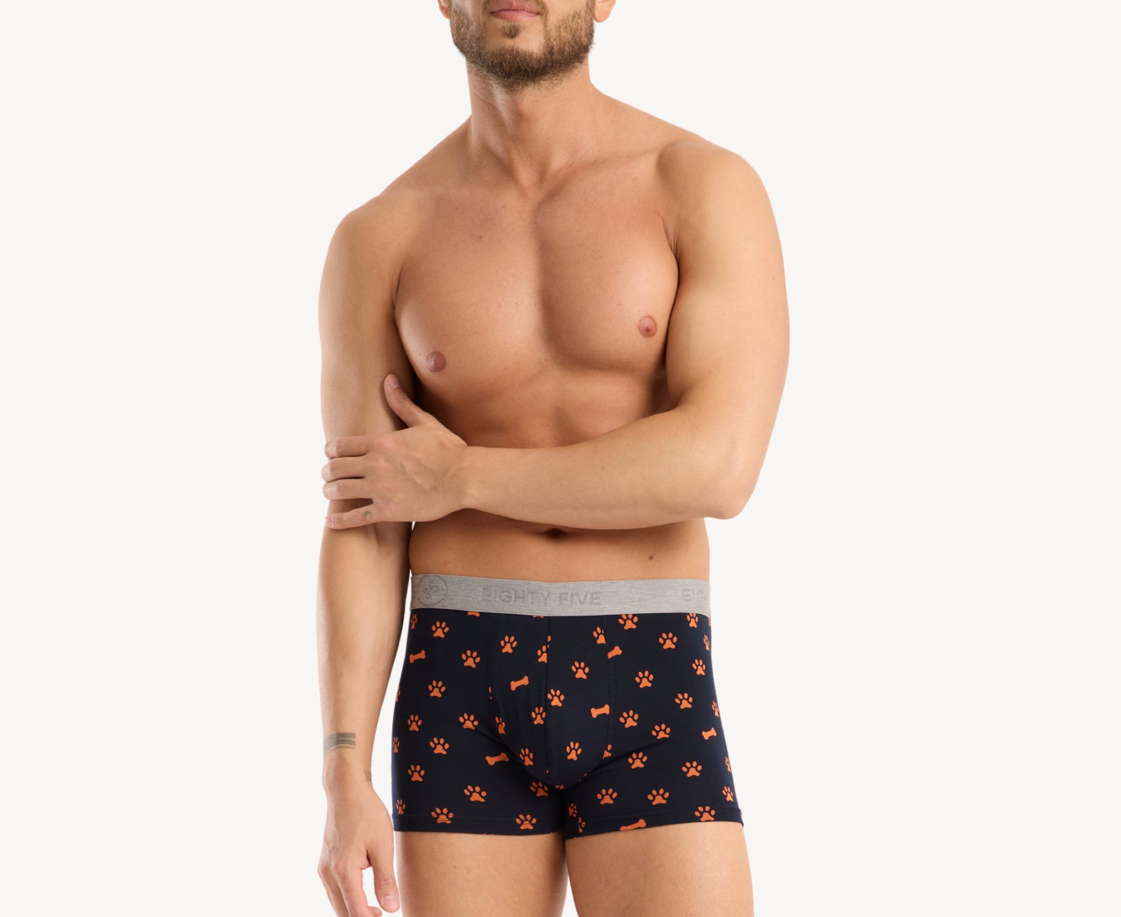 Front view of male model wearing men’s 95% cotton boxer brief in navy with orange paws and bones print, showing smooth waistband and contoured fit