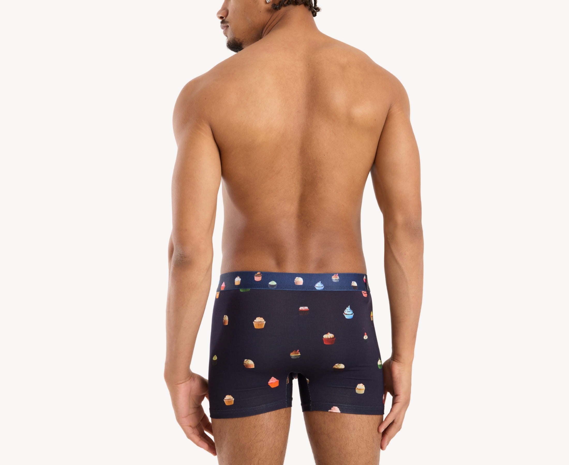 Back view of model wearing men’s 95% micromodal boxer brief in navy with cupcake print, smooth waistband and rear detail