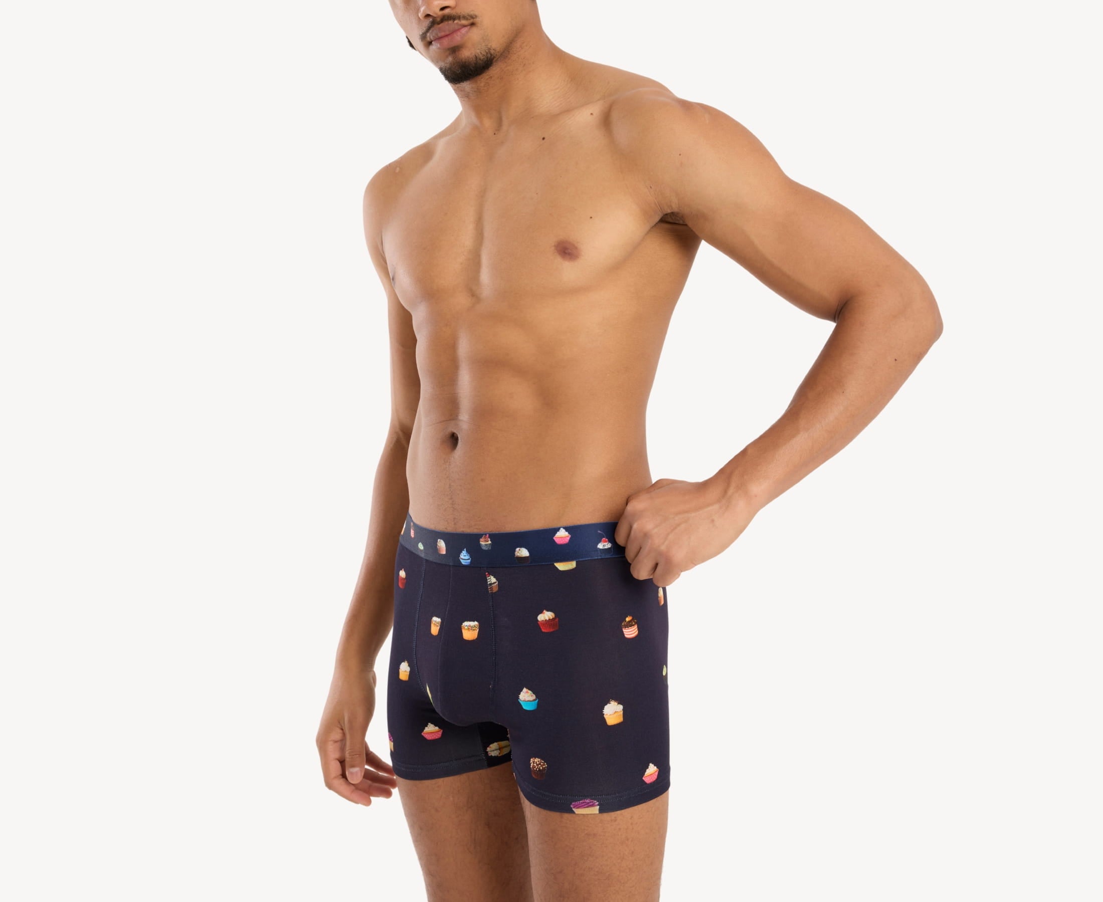 Side view of model wearing men’s 95% micromodal boxer brief in navy with cupcake print, contoured pouch and tailored leg cut