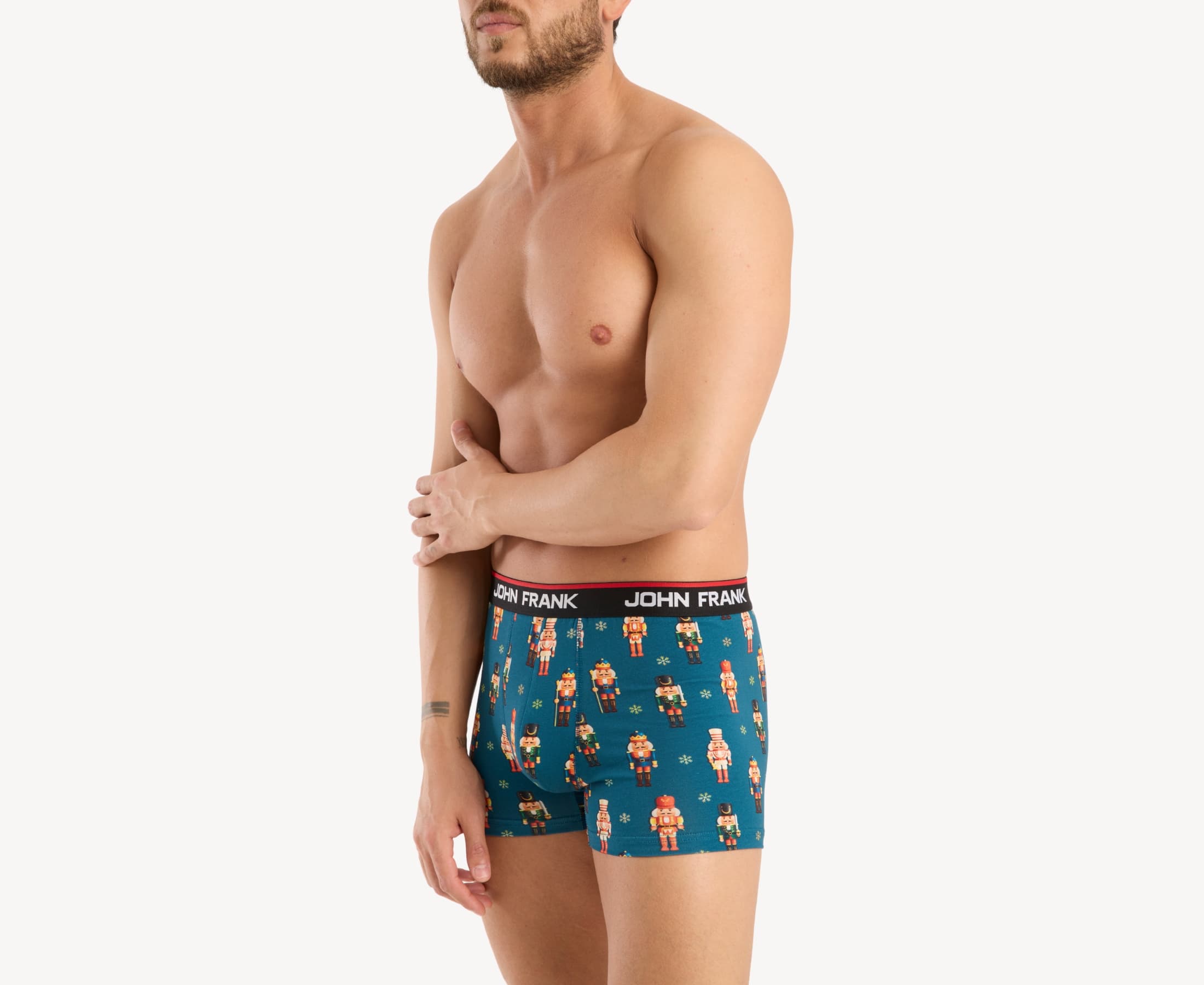 Front side view of male model wearing men’s 95% cotton boxer brief in teal with colorful nutcrackers print, showing smooth waistband and contoured fit