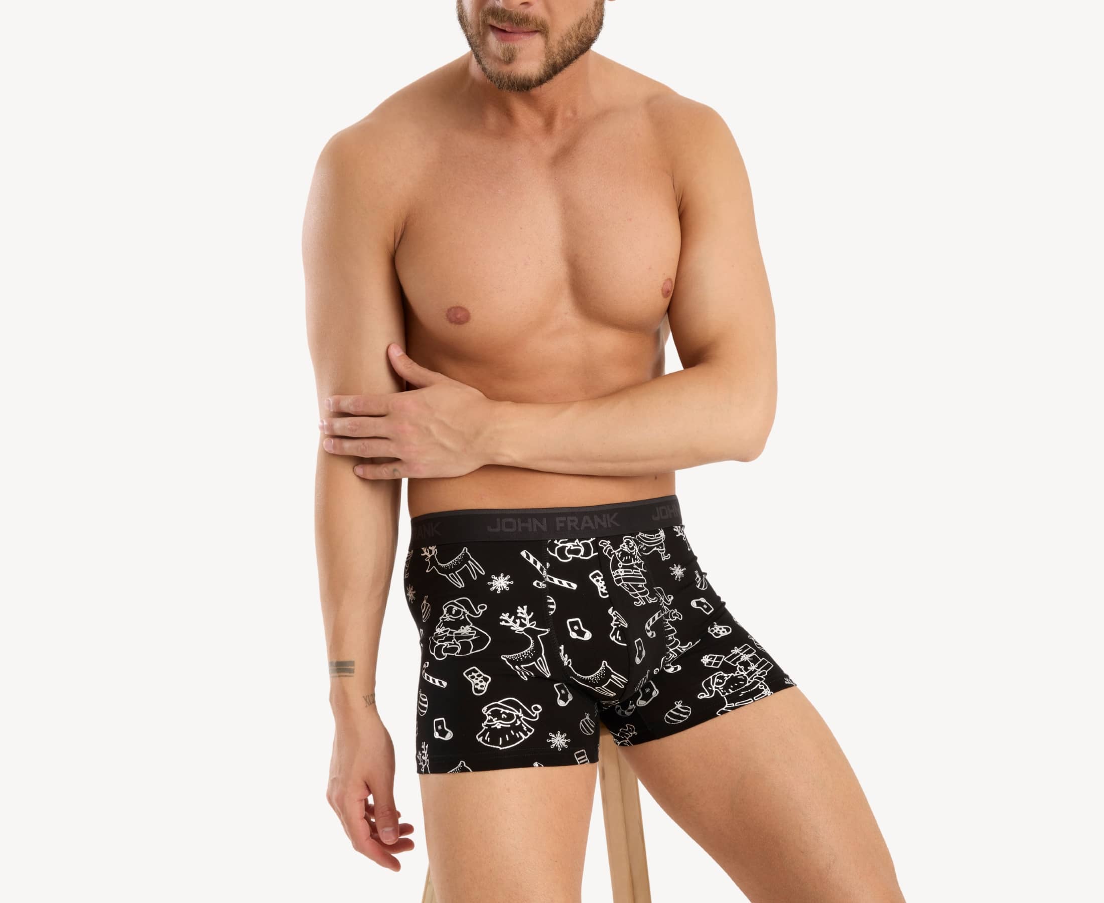 Front view of male model wearing men’s 95% cotton boxer brief in black with shiny silver Christmas doodles print, showing smooth waistband and contoured fit