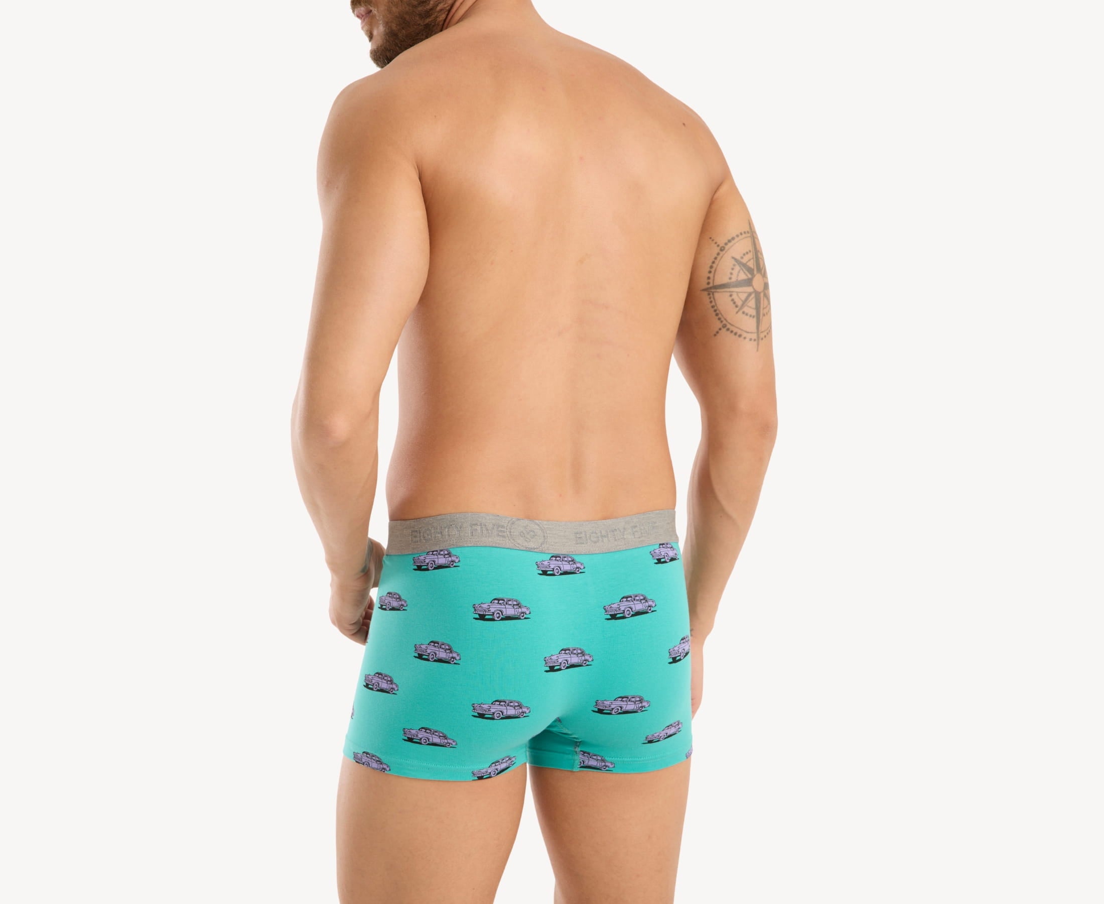 Back view of male model wearing men’s 95% cotton boxer brief in turquoise with pink vintage car print, showing smooth waistband and contoured fit.