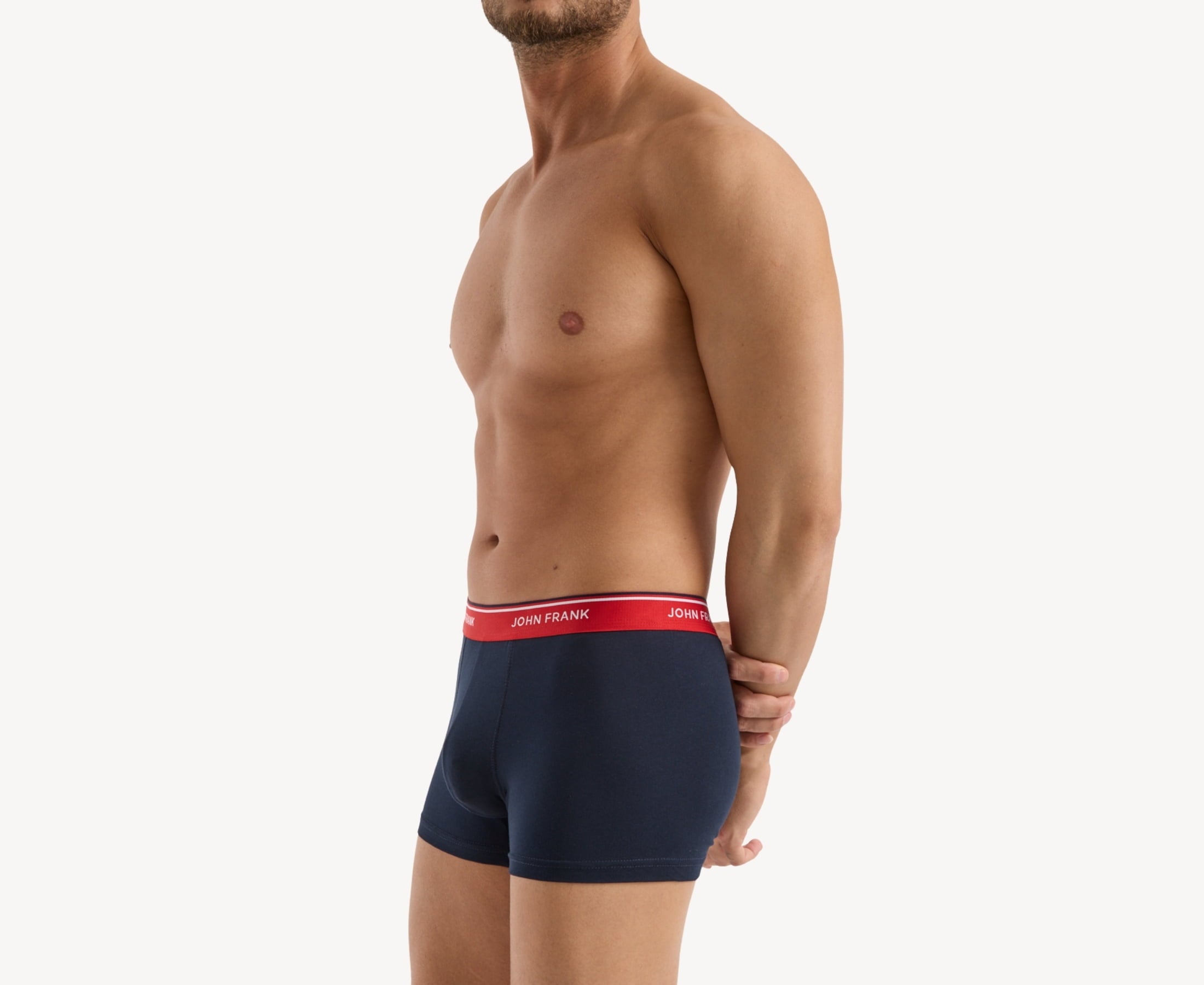 Side view of model wearing men’s 95% cotton boxer brief in midnight blue with cherry red striped waistband, contoured pouch, and tailored leg cut