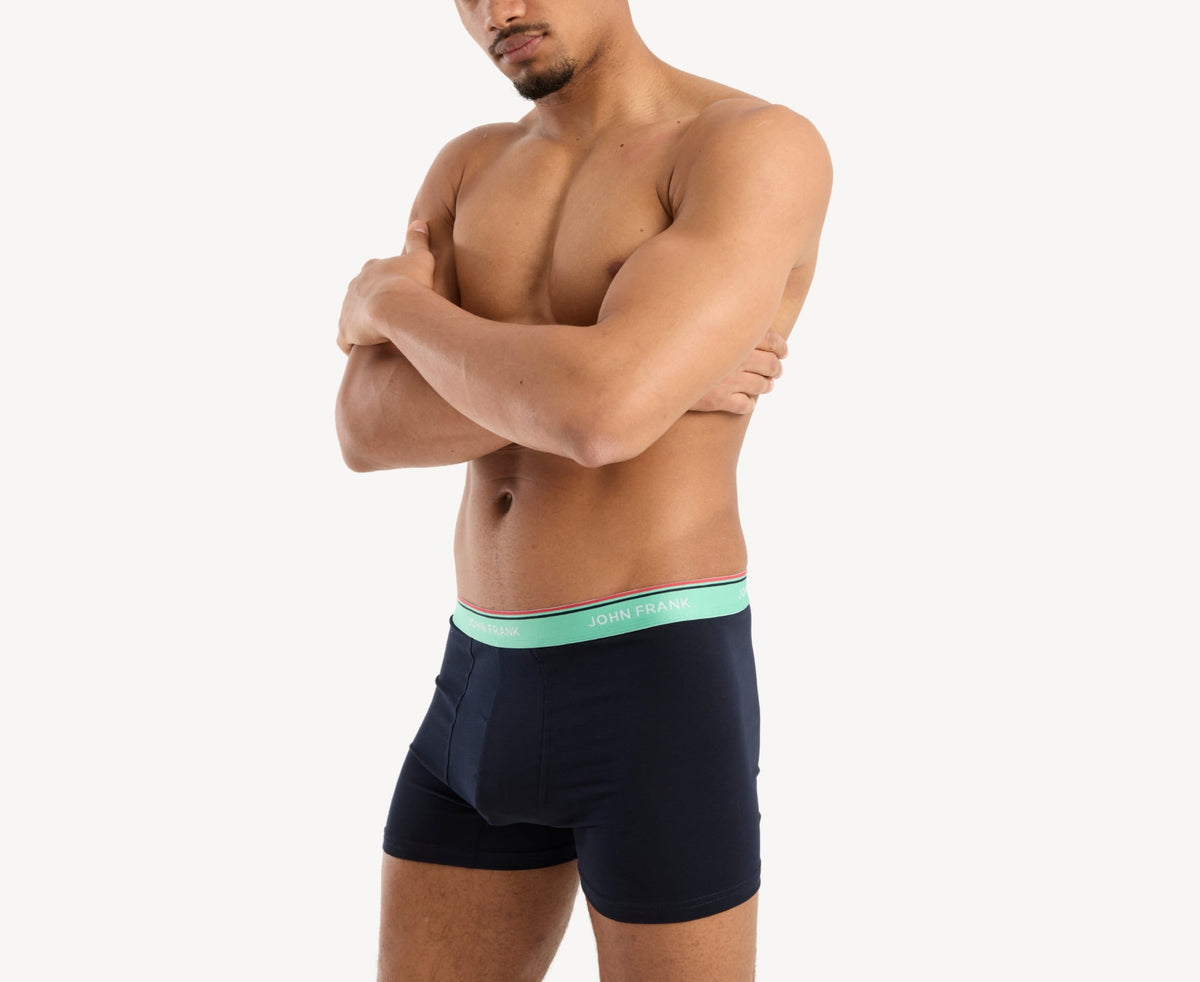 Side view of model wearing men’s 95% cotton boxer brief in midnight blue with sea green striped waistband, contoured pouch, and tailored leg cut