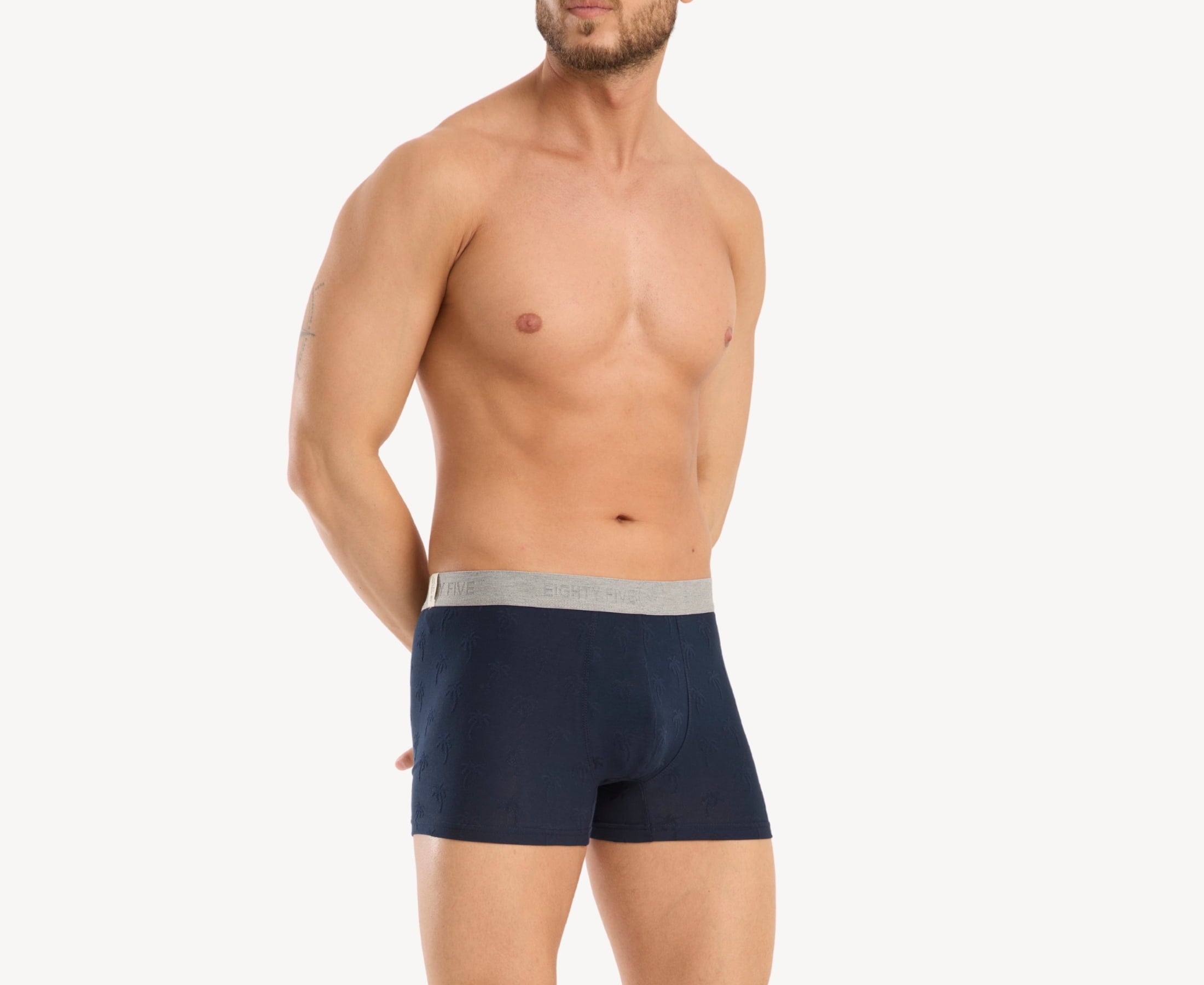 Side view of model wearing men’s 95% cotton boxer brief in navy with jacquard palms pattern, showcasing contoured pouch, and tailored leg cut