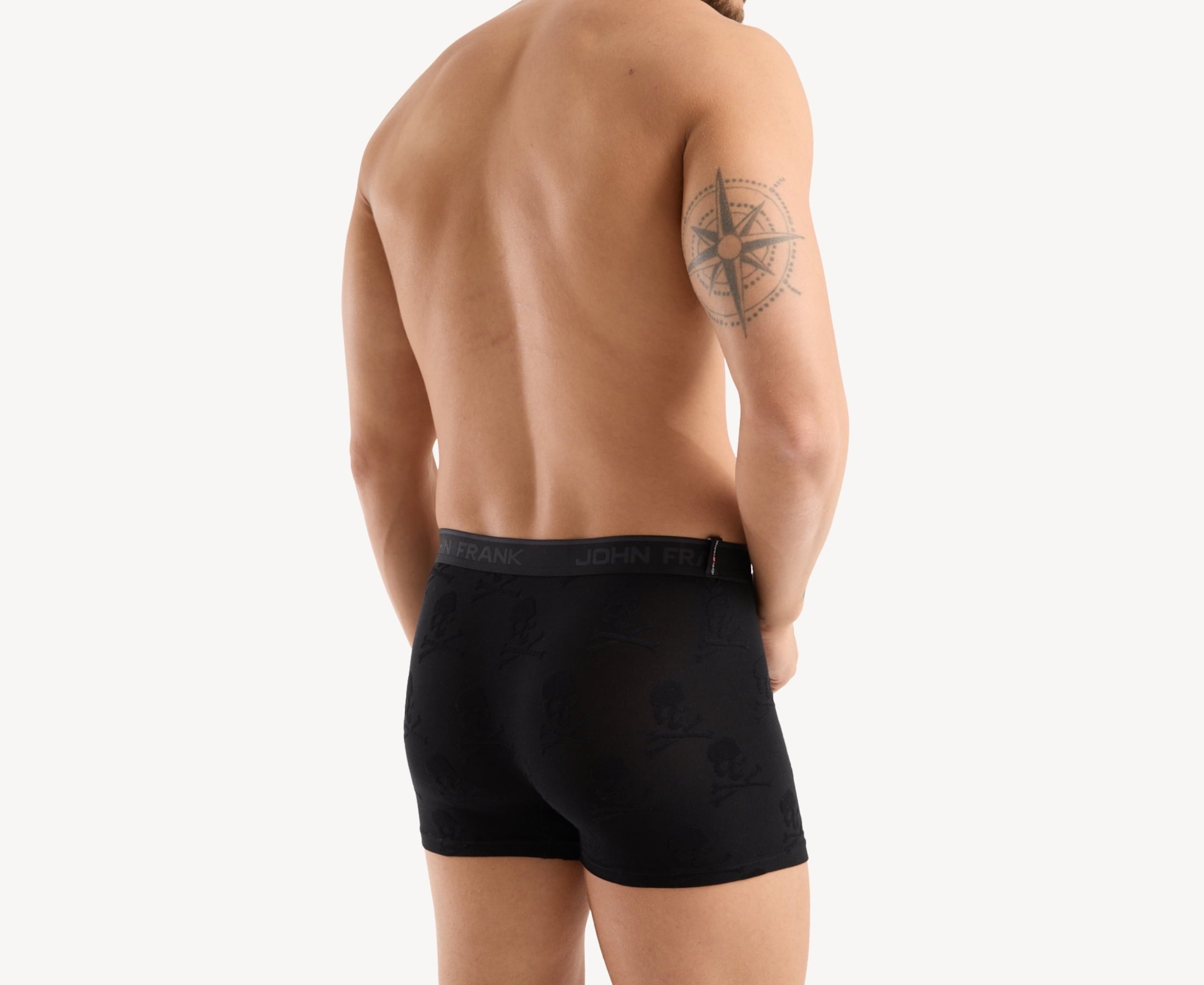 Back view of model wearing men’s 95% micromodal boxer brief in black with jacquard skull and cross bones pattern, showcasing smooth waistband and rear detail