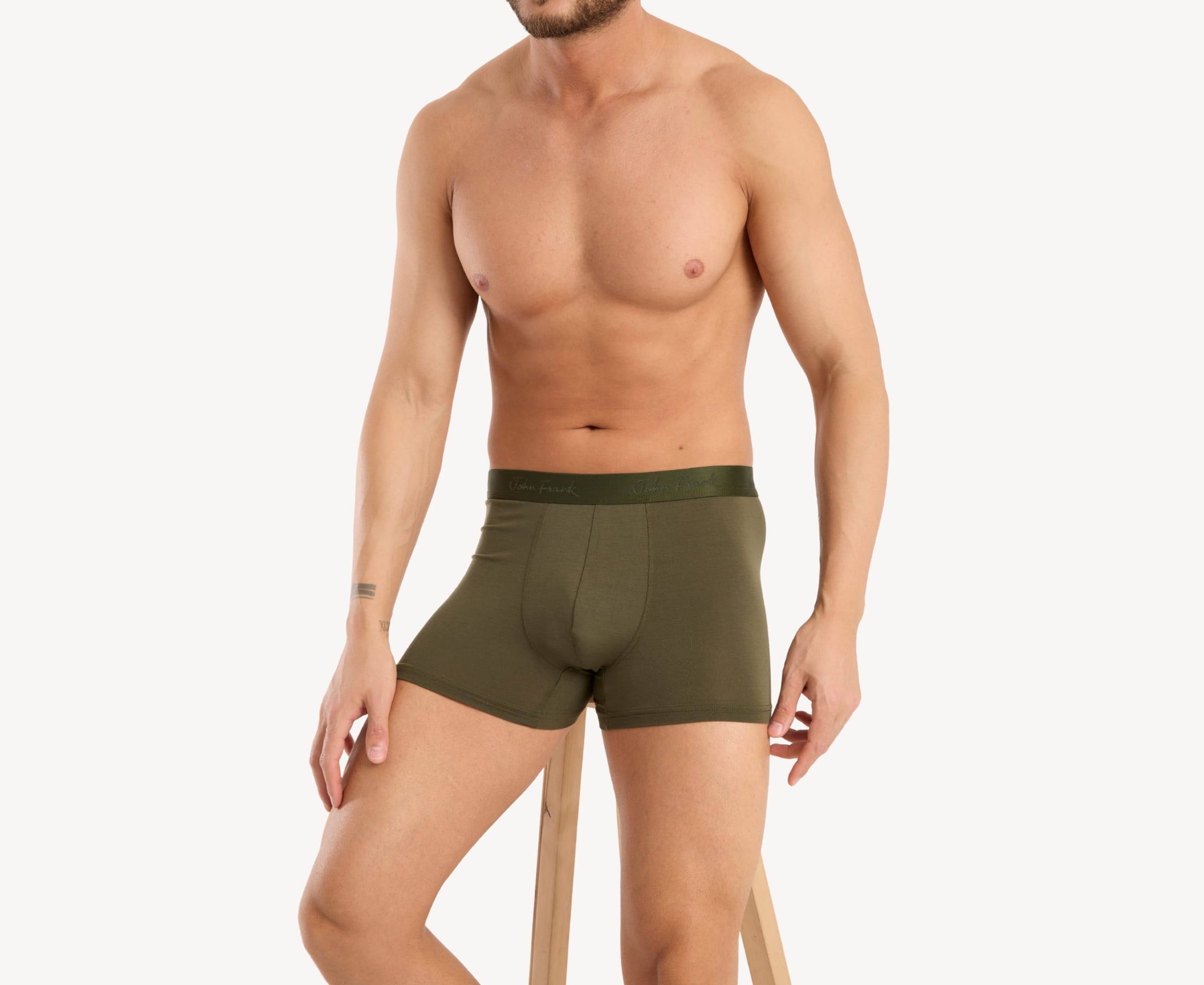 Front seated view of model wearing men’s 95% micromodal boxer brief in olive with tonal waistband featuring subtle sheen, and soft stretch