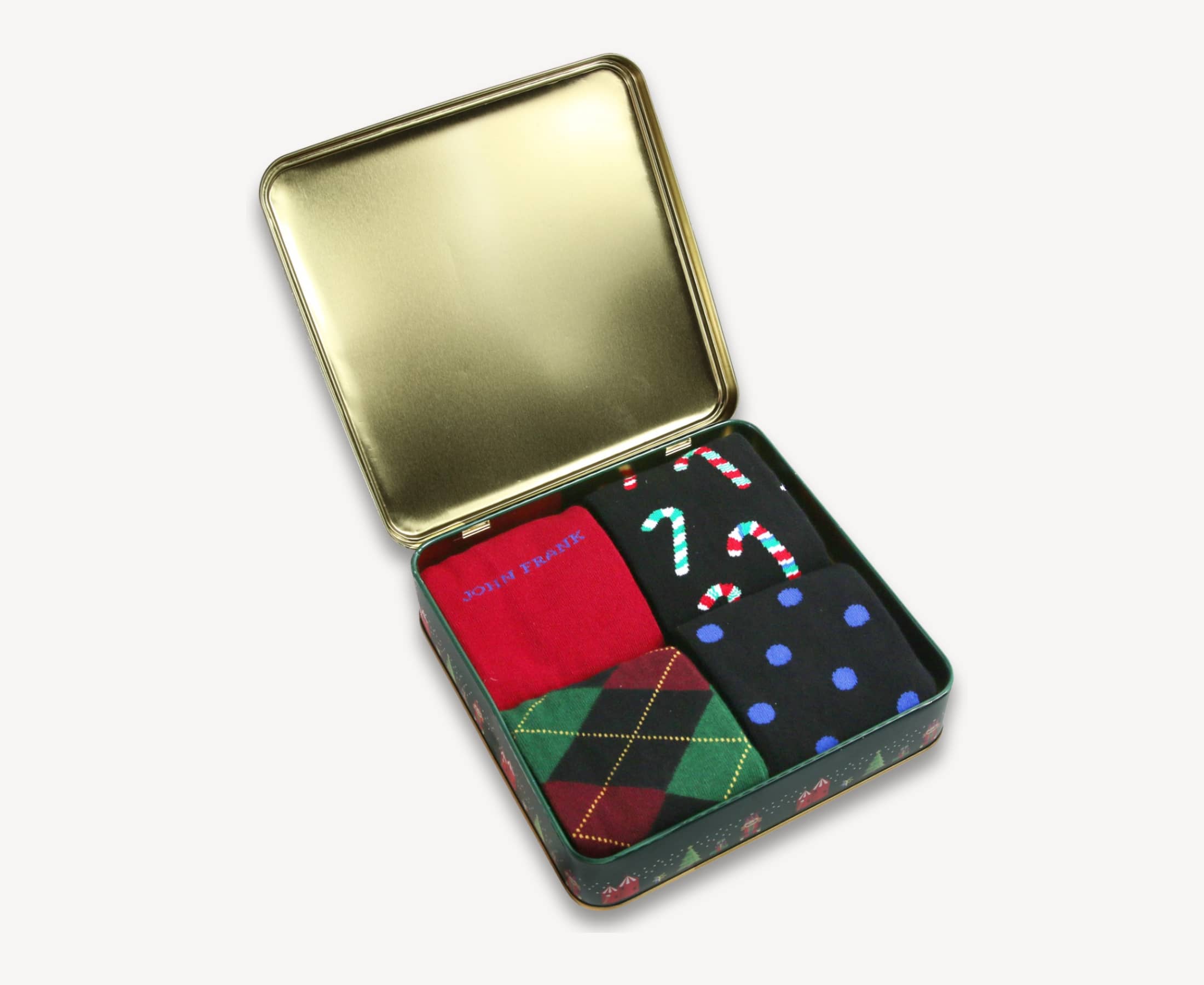 Open view of Holiday Classics Sock Tin showing four folded cotton crew socks in holiday prints and solids — candy cane, argyle, frosty dots, and Rudolph red — inside a gold-lined gift box.